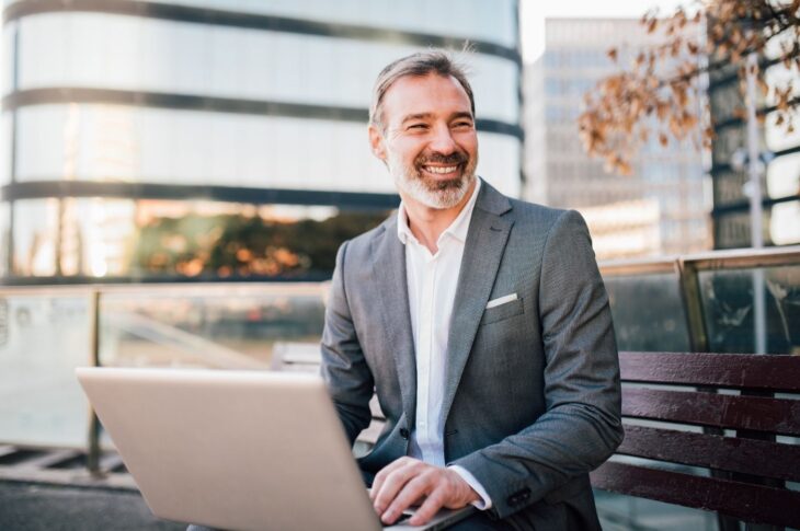 Happy Businessman Using Laptop Outdoors
